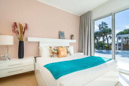 a bedroom with a bed and a large window at Caya di Bista Bunita 6 in Palm-Eagle Beach