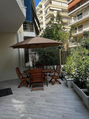 eine Terrasse mit einem Tisch, Stühlen und einem Sonnenschirm in der Unterkunft Olivia Luxury Apartment Palio Faliro in Athen