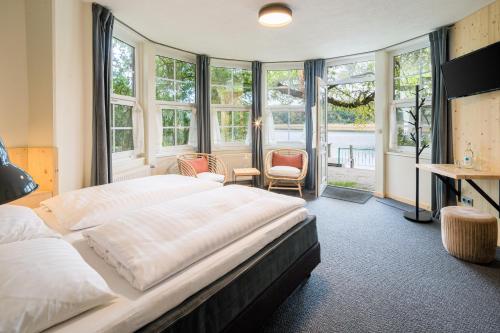 a bedroom with a bed and a desk and windows at Romantischer Seegasthof & Hotel Altes Zollhaus in Feldberg