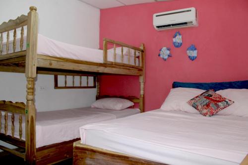 2 Etagenbetten in einem Zimmer mit rosa Wänden in der Unterkunft Kali Hostal in La Libertad
