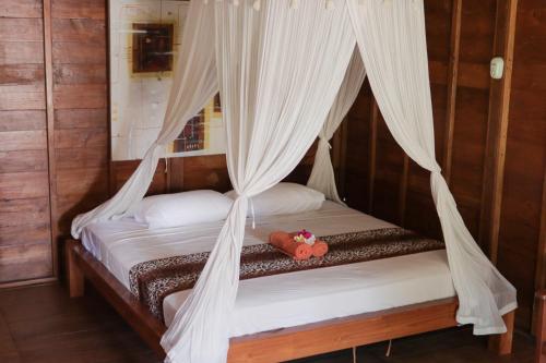 een slaapkamer met een bed met een teddybeer erop bij Yut's Inn Flower Paradise Gili Gede in Gili Gede