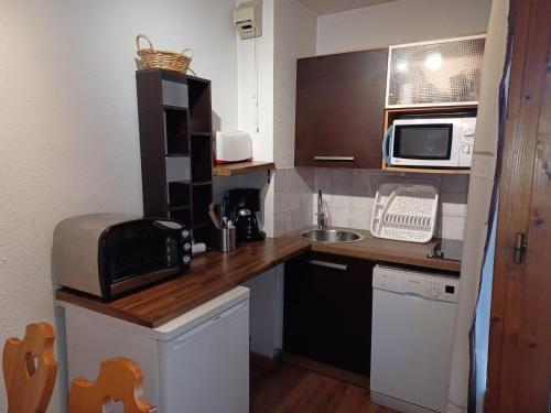 une petite cuisine avec un évier et un micro-ondes dans l'établissement Studio cosy avec parking couvert, balcon et vue montagne - FR-1-512-121, à Brides-les-Bains