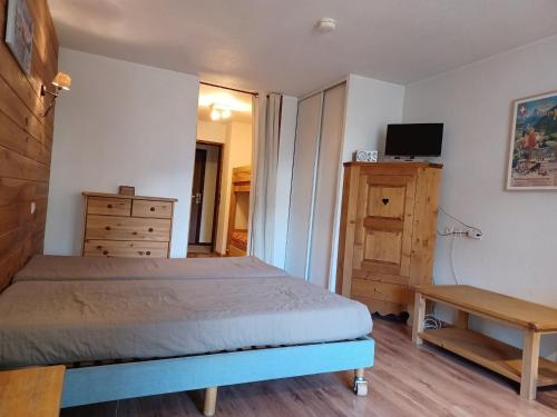 - une chambre avec un lit, une commode et une télévision dans l'établissement Studio cosy avec parking couvert, balcon et vue montagne - FR-1-512-121, à Brides-les-Bains