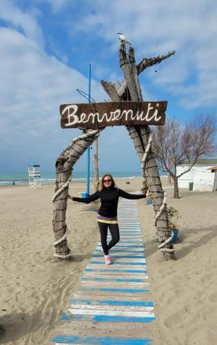 a woman is standing under a sign on the beach at Romantische Villa am Meer mit Kamin Zoomarine Cinecittà World in Torvaianica