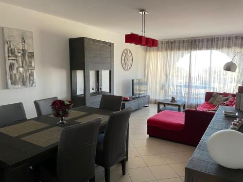 a living room with a table and a red couch at Appartement T3 Les eucalyptus in LʼÎle-Rousse