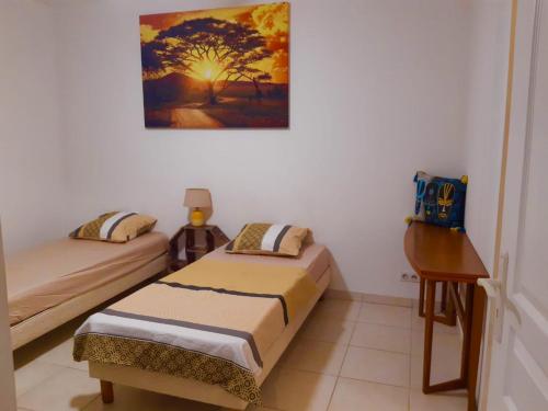Habitación con 2 camas individuales y escritorio. en Chambre privée près des plus belles plages du Nord en La Trinité
