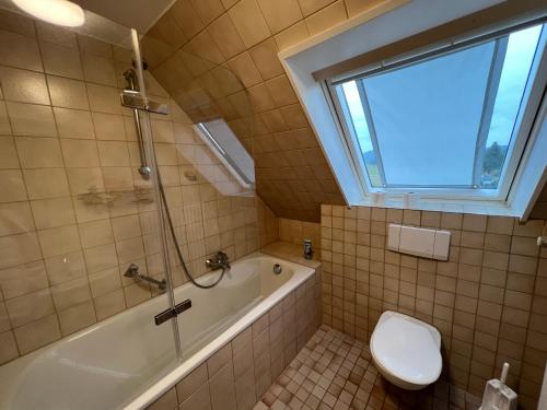 La salle de bains est pourvue d'une baignoire, de toilettes et d'une fenêtre. dans l'établissement Ferienhaus Frei 3 Budget, à Titisee-Neustadt