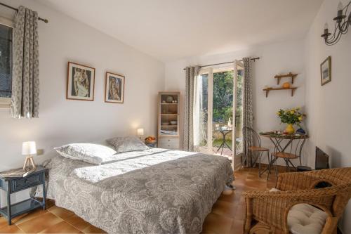 a bedroom with a bed and a chair and a window at Le Mas des Gardettes in Saint-Paul-de-Vence