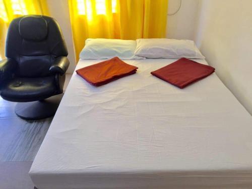 ein Bett mit zwei Kissen und einem Stuhl in einem Zimmer in der Unterkunft Harvey's Place in Cagayan de Oro