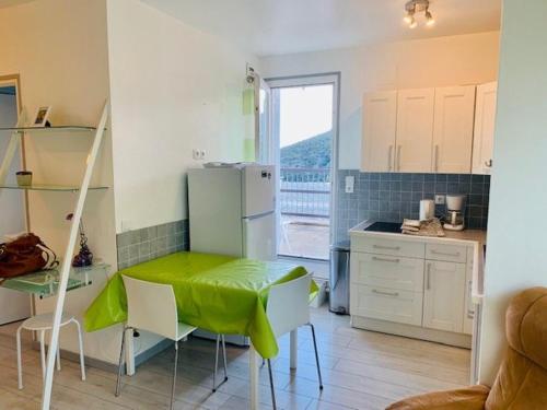 une cuisine avec une table et un chiffon vert dans l'établissement Studio avec Balcon et Terrasse, Parking, à 50m des Cures – 2 étoiles – Animaux Bienvenus - FR-1-703-123, à Amélie-les-Bains-Palalda