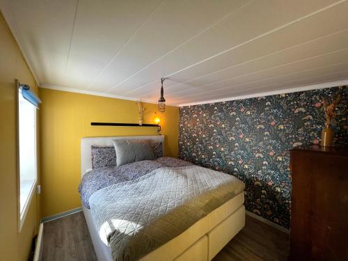 1 dormitorio con cama y pared con papel pintado con motivos florales en High Noon Westernranch Holidayhouse, en Ljusdal