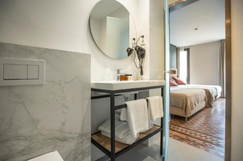 a bathroom with a sink and a mirror and a bed at Fontanella By BCN URBAN Rooms in Barcelona