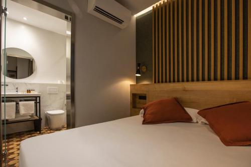 a bedroom with a white bed and a bathroom at Fontanella By BCN URBAN Rooms in Barcelona
