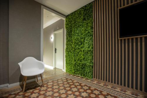 a white chair in a room with a green wall at Fontanella By BCN URBAN Rooms in Barcelona