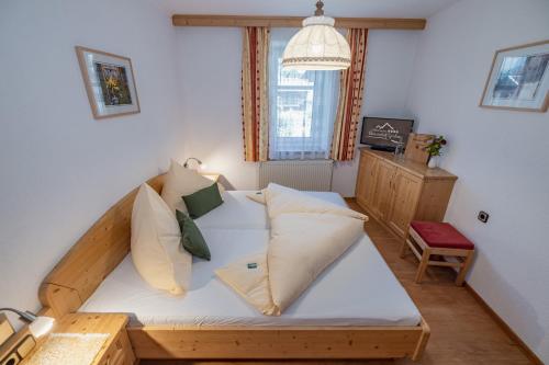 Schlafzimmer mit einem Holzbett mit weißer Bettwäsche und Kissen in der Unterkunft Erlebenswert Bauernhof Gruber in Sankt Lorenzen im Lesachtal