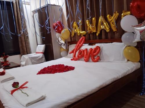 a bed with balloons and a sign that says happy love at Vinee's Kitchen and Motel in Koynanagar