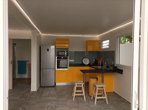 a kitchen with yellow cabinets and a counter with stools at Lez'arlet Plage in Les Anses-dʼArlets