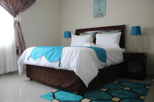 a bedroom with a large bed with white and blue at Deluxe Guest House in Gaborone