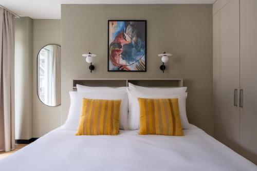 a bedroom with a large white bed with yellow pillows at Numa Zurich Craft in Zürich