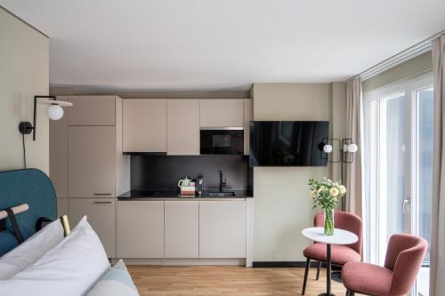 a kitchen with white cabinets and a table and chairs at Numa Zurich Craft in Zürich