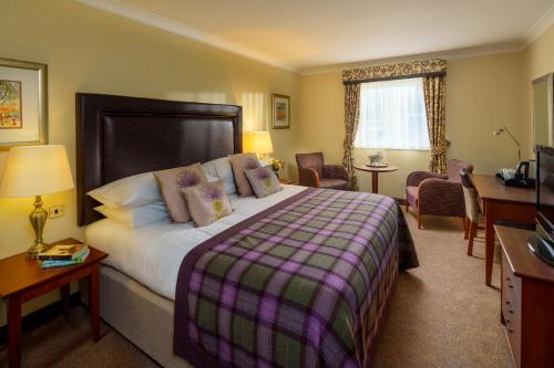 a hotel room with a large bed and a desk at Macdonald Tickled Trout Hotel in Preston