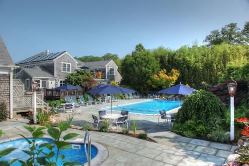 a swimming pool with patio furniture and umbrellas at Pleasant Bay Village Resort in Chatham