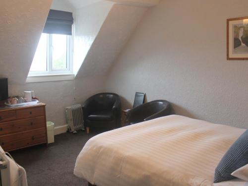 a bedroom with two chairs and a bed and a window at Hazeldene Guest House - with Free Offsite Health Club in Bowness-on-Windermere