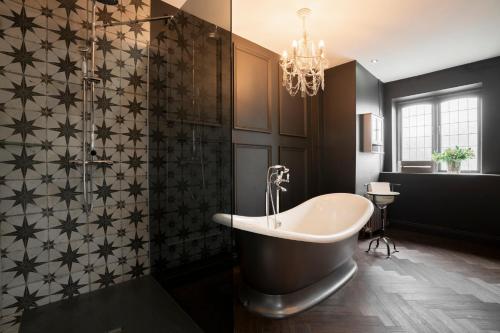a bathroom with a bath tub and a chandelier at Derwent Manor Boutique Hotel in Consett