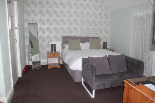 a bedroom with a bed and a chair and a mirror at Hazeldene Guest House - with Free Offsite Health Club in Bowness-on-Windermere