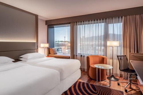 a hotel room with two beds and a desk and a window at Sheraton Zürich Hotel in Zurich