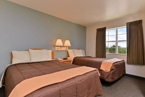 una camera d'albergo con due letti e una finestra di Americas Best Value Inn & Suites-Winnie a Winnie