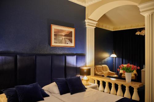 1 dormitorio con cama y pared azul en Hotel Royal, en Gliwice