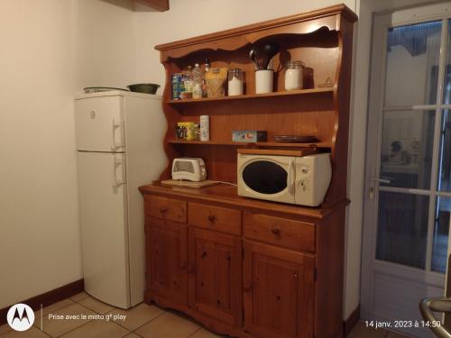 - un four micro-ondes sur une armoire en bois à côté d'un réfrigérateur dans l'établissement Maison au pays des milles étangs, à Saint-Michel-en-Brenne