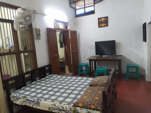 a bedroom with a bed and a desk and a television at Kallidai Home Stay in Ambāsamudram