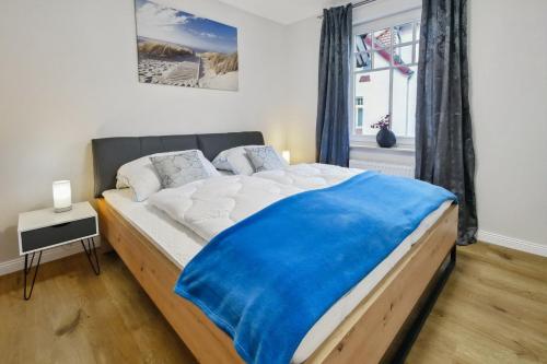 a bedroom with a large bed with a blue blanket on it at Ostseewelle Wohnung 15 in Kühlungsborn