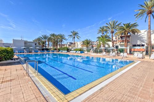 a large swimming pool with palm trees and buildings at Exclusive 1 bedroom apartment with a Pool in Arona