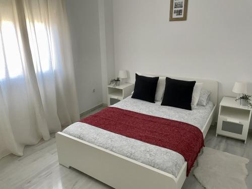 a white bedroom with a large bed with black pillows at Apartamento Liru Bormujos, a 5 minutos de Sevilla in Bormujos