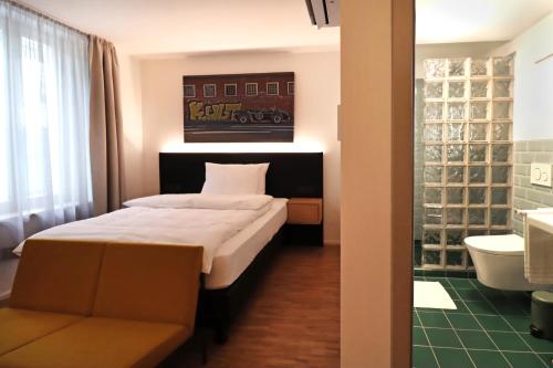 1 dormitorio con 1 cama grande y baño en S12 - Boardinghouse by Hotel Trezor en Singen