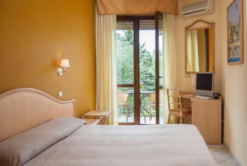 a bedroom with a bed and a television and a balcony at Hotel Orion in Villammare