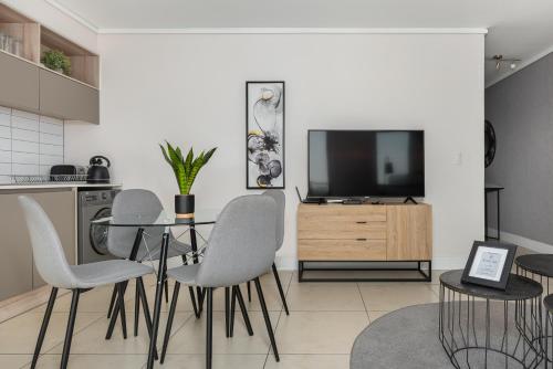 a living room with a table and chairs and a television at Waters Edge Apartments in Cape Town