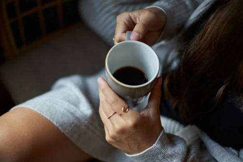 a woman is holding a cup of coffee at Cocoon Stachus in Munich