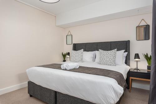 a bedroom with a large bed with white sheets and pillows at Waters Edge Apartments in Cape Town