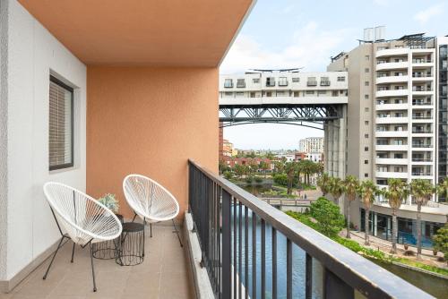 a balcony with two chairs and a view of a bridge at Waters Edge Apartments in Cape Town