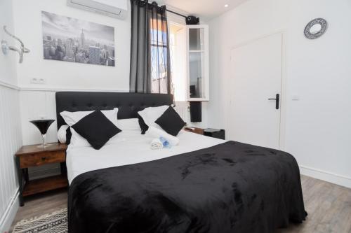 a bedroom with a black and white bed and a window at Hostellerie LE PANEL in Mandelieu-la-Napoule