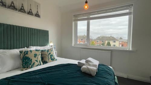 Fully Serviced Three Bed House in Durham في دورهام: غرفة نوم مع سرير مع اللوح الأمامي الأخضر ونافذة