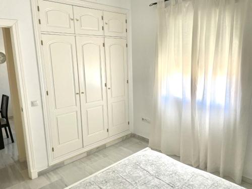 Habitación con armario blanco y cortina en Apartamento Liru Bormujos, a 5 minutos de Sevilla en Bormujos