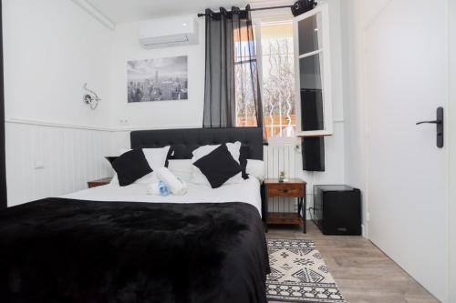 a bedroom with a black and white bed and a window at Hostellerie LE PANEL in Mandelieu-la-Napoule