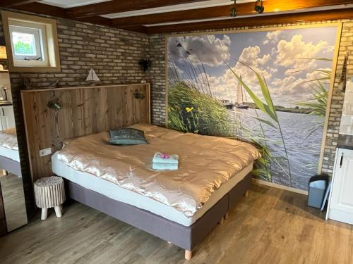 a bedroom with a bed with a painting on the wall at It Kapteinshûske in Heeg