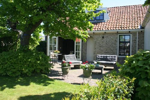 a patio with two chairs and a bench in a yard at It Kapteinshûske in Heeg