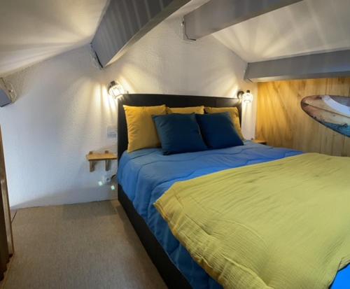 une chambre avec un lit avec des oreillers bleus et jaunes dans l'établissement HAMEAU DES CAPELLANS Duplex avec superbe vue marina piscine wifi gratuit parking gratuit, à Saint-Cyprien